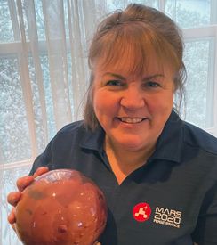 Photo of Kathy Benison with model of Mars disguised as a bowling ball